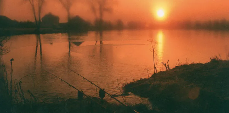 Apus de soare reflectat într-un lac, cu malul în umbră